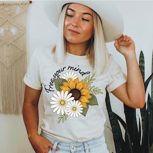 May include: A white t-shirt with a sunflower and daisy design and the text "Free your mind".