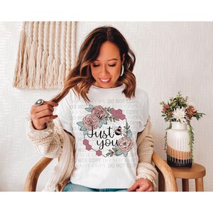 May include: White t-shirt with a floral design and the text "Just you" in a pink hexagon. The design features a bee, flowers, and honeycomb.
