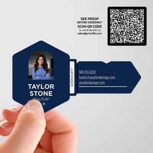 May include: A navy blue key-shaped business card held by a hand. The card features a photo of a woman, the name "TAYLOR STONE, REALTOR", and contact information. A QR code and text "SEE PROOF BEFORE ORDERING? SCAN QR CODE" are also visible.