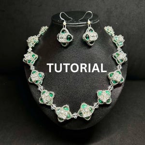 Puede incluir: Un collar y pendientes a juego de cuentas plateadas y verdes. El collar está hecho de pequeñas cuentas cuadradas con un centro verde y un borde plateado. Los pendientes son de diseño similar, con una sola cuenta cuadrada colgando de un gancho plateado.