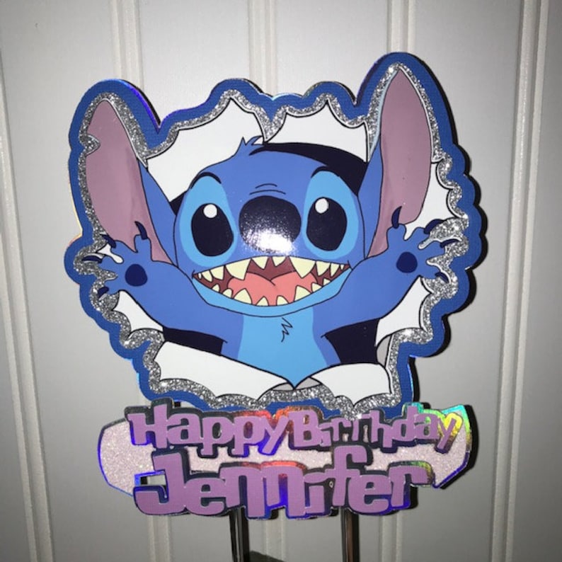 Może przedstawiać: Niebiesko-fioletowy topper na tort przedstawiający Stitch'a z Lilo & Stitch, kt&oacute;ry wygląda z dziury z napisem "Happy Birthday Jennifer".