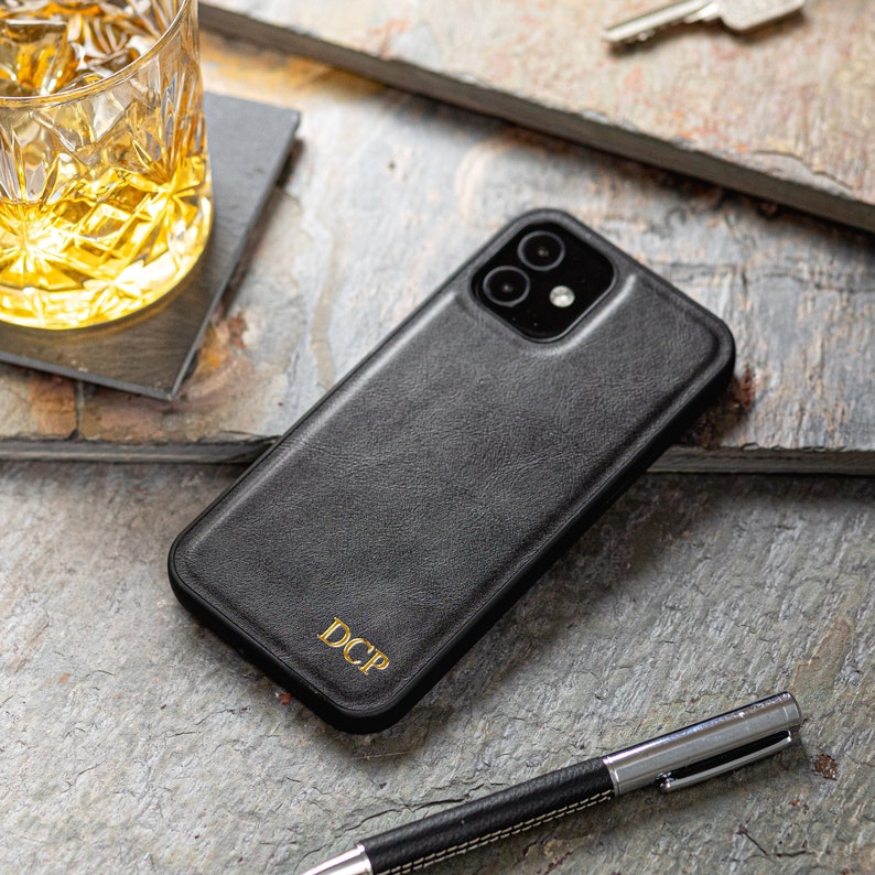 May include: Black leather phone case with a gold embossed monogram "DCP".