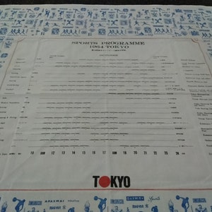 Może przedstawiać: Biało-niebieski program sportowy dla Igrzysk Olimpijskich w Tokio w 1964 roku. Program zawiera listę dyscyplin sportowych i daty zawodów. Program otoczony jest obramowaniem z niebieskich i białych ludzików reprezentujących różne dyscypliny sportowe.