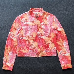 Puede incluir: Una chaqueta con cierre de cremallera con estampado floral rojo y naranja.