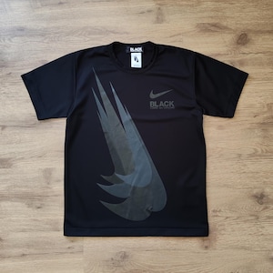 May include: Black t-shirt with a large graphic print of a stylized Nike swoosh in gray. The text "BLACK" is printed below the swoosh.