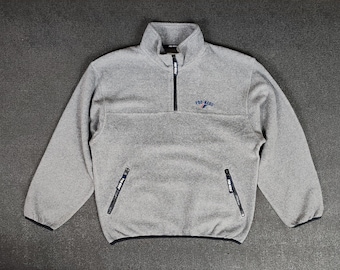 May include: A gray fleece pullover with a half-zip closure and a "Pro-Keds" logo on the chest. The pullover has two zippered pockets on the front.