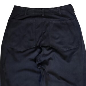 Puede incluir: Primer plano de la parte trasera de unos pantalones negros. Los pantalones tienen dos bolsillos cuadrados grandes y una cintura con trabillas. La tela parece ser un material oscuro y resistente.