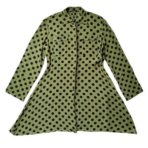 May include: A long-sleeved button-down shirt in olive green featuring a repeating black polka dot pattern. The garment includes a classic collar, a full-length front button placket, and two chest pockets with buttoned flaps on the front.