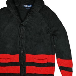 May include: Black cardigan sweater with red stripes and a shawl collar. The sweater has two pockets and buttons down the front. The label reads "Polo by Ralph Lauren" and "L".