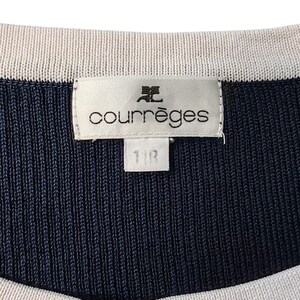 May include: A navy blue and cream ribbed knit garment featuring a white rectangular brand label stitched at the neckline. The label displays the text courr&egrave;ges with a logo above it and a smaller tag below with the text 11R printed in black.