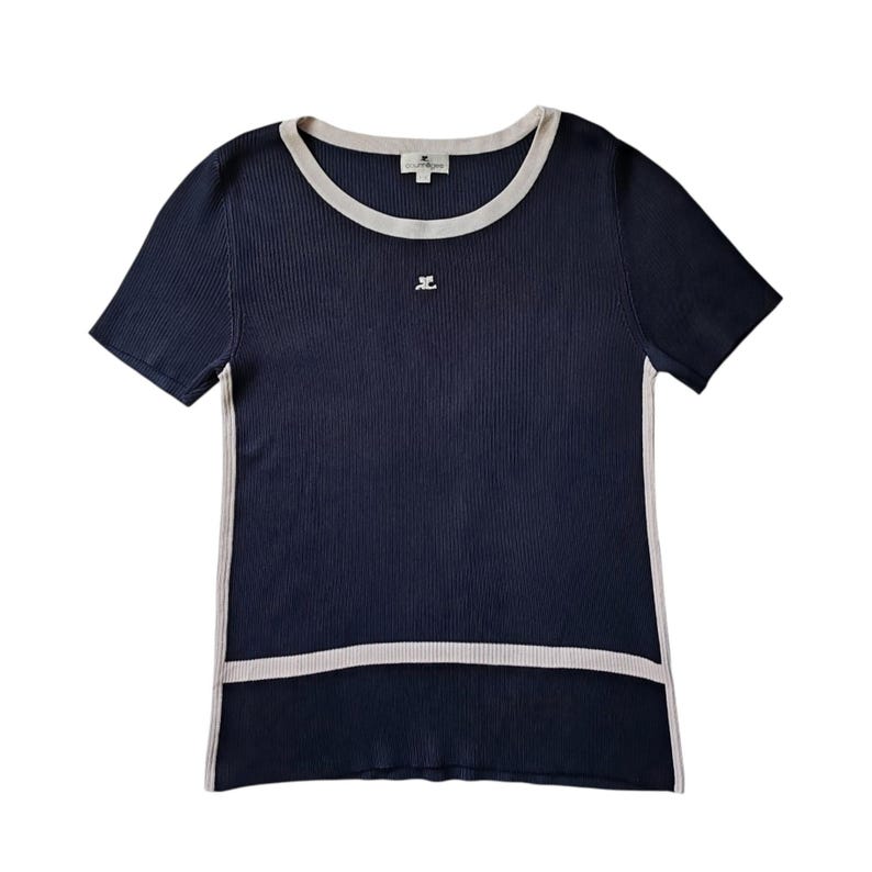 May include: A navy blue short-sleeved ribbed knit top featuring a round neckline with beige trim, matching beige side panels, and a horizontal beige band near the hem. A small white logo is embroidered on the chest, and a brand label is at the neck.