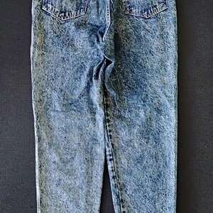 Może przedstawiać: Jasnoniebieskie dżinsy z efektem acid wash z czarną metką z napisem "River Collection Original Brand".