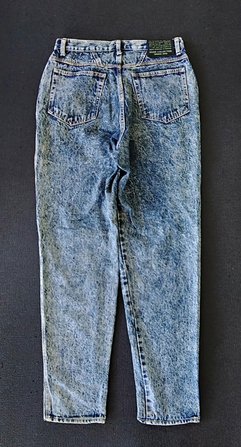 Może przedstawiać: Jasnoniebieskie dżinsy z efektem acid wash z czarną metką z napisem "River Collection Original Brand".