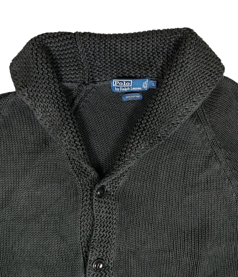 May include: A dark green knitted cardigan with a shawl collar and button closure. The label reads "Polo by Ralph Lauren" and "100% Cotton".