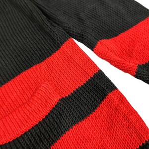May include: A black and red striped knitted jumper. The jumper is made of a soft, comfortable material and has a classic striped design.