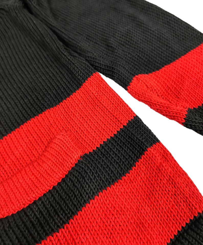 May include: A black and red striped knitted jumper. The jumper is made of a soft, comfortable material and has a classic striped design.