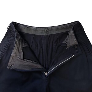 Puede incluir: Primer plano de pantalones azul marino con cremallera abierta y cierre de bot&oacute;n. Los pantalones tienen un dise&ntilde;o cl&aacute;sico con costuras visibles y una cinturilla reforzada. El forro interior es visible.