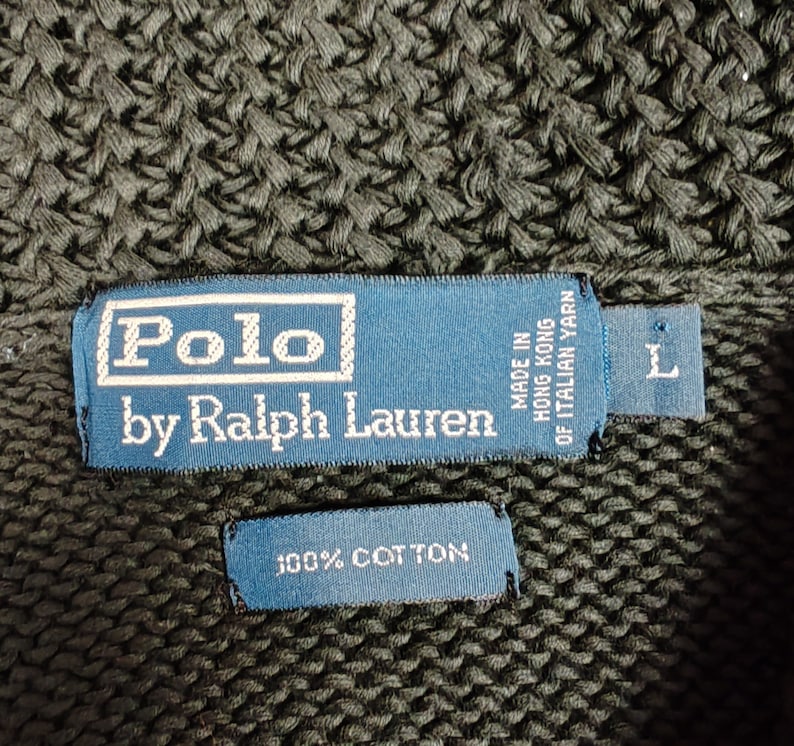 May include: A dark green knitted sweater with a blue label that reads "Polo by Ralph Lauren" and "Made in Hong Kong of Italian Yarn". The label also has a size "L" tag. A smaller blue label reads "100% Cotton".
