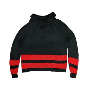 May include: Black turtleneck sweater with red and black stripes at the bottom.