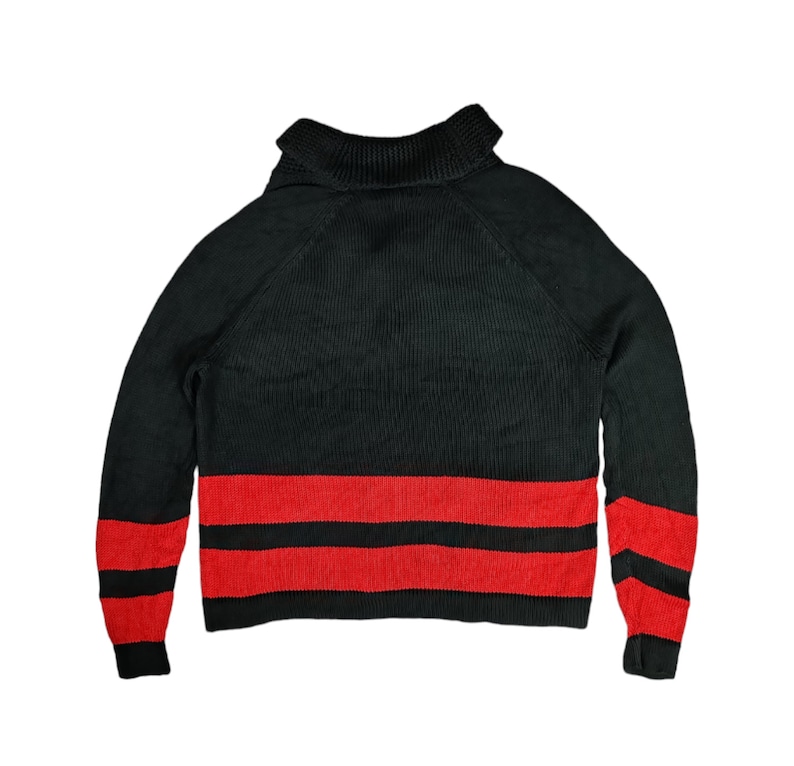 May include: Black turtleneck sweater with red and black stripes at the bottom.