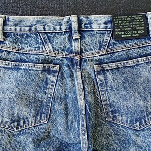 Może przedstawiać: Dżinsy z niebieskiego denimu z efektem acid wash, z tylną kieszenią i metką z napisem "River Collection Original Jeans" oraz "Do życia na świeżym powietrzu i w mieście, casualowy styl zapewniający komfort i lepsze dopasowanie. Teraz spotykamy się ze świeżym odczuciem - Dołączamy do ludzi o wysokiej wrażliwości na modę."