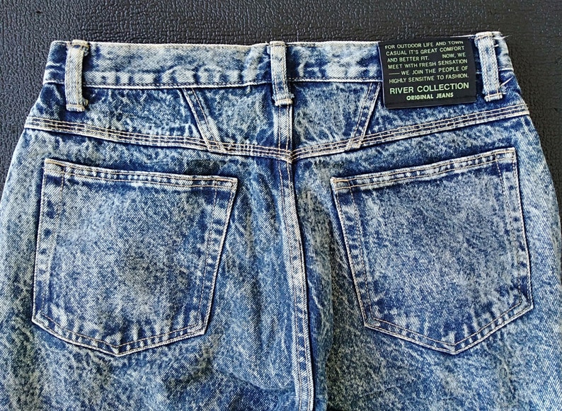 Może przedstawiać: Dżinsy z niebieskiego denimu z efektem acid wash, z tylną kieszenią i metką z napisem "River Collection Original Jeans" oraz "Do życia na świeżym powietrzu i w mieście, casualowy styl zapewniający komfort i lepsze dopasowanie. Teraz spotykamy się ze świeżym odczuciem - Dołączamy do ludzi o wysokiej wrażliwości na modę."
