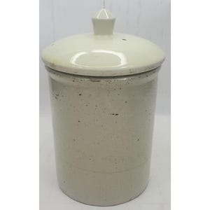 May include: A cylindrical ceramic canister with a speckled off-white glaze and a matching lid featuring a pointed knob handle. The container has a smooth, glossy finish with visible dark flecks throughout the surface and a simple, straight-sided design.