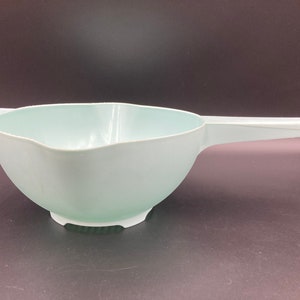 May include: A light blue plastic colander with a handle. The colander has a scalloped edge and a wide, shallow bowl.