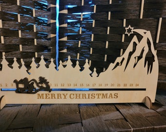 May include: Wooden Christmas advent calendar with a mountain and tree silhouette design. Features a sleigh and reindeer, with the words "MERRY CHRISTMAS" and numbers 1-24. A festive holiday decoration.