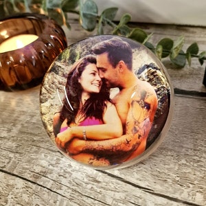 May include: A clear glass paperweight with a photo of a couple embracing. The photo is in color and shows the couple in a natural setting.