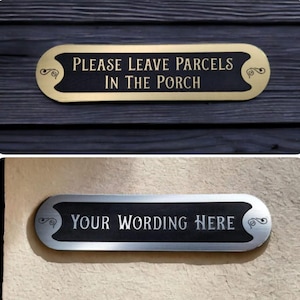 Op de afbeelding: Twee ovale borden, een gouden en een zilveren, met decoratieve krulwerk. Het bovenste bord staat "Laat pakketten in de veranda achter". Het onderste bord staat "Uw tekst hier".