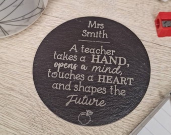 May include: A round, dark gray slate coaster with the name "Mrs Smith" and the quote "A teacher takes a HAND, opens a mind, touches a HEART and shapes the Future." A small apple graphic is at the bottom.