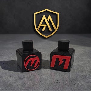 以下が含まれることがあります： 赤色のロゴが付いた2つの黒いボトルストッパー。1つは円形、もう1つは正方形です。各ストッパーは円筒形のトップと正方形のベースを備えています。背景には金のロゴが見えます。