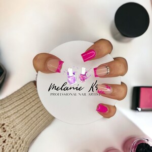 May include: Close-up of a hand with pink and white nail art. The nails are long and oval shaped. The nail art features a pink french tip with a white base and a pink flower design. The hand is holding a white circle with the text "Melanie K's Professional Nail Artist" on it.