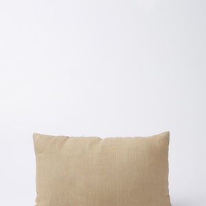 May include: A rectangular beige linen pillow with a subtle texture. The pillow is on a white background.