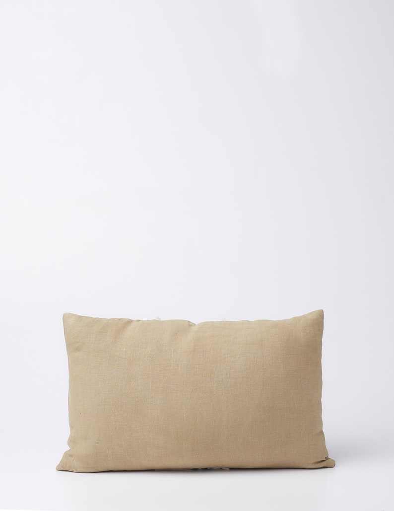 May include: A rectangular beige linen pillow with a subtle texture. The pillow is on a white background.