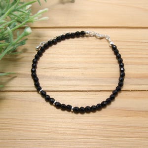Peut inclure: Un bracelet en perles d'onyx noir avec des accents argentés et une fermeture à fermoir.