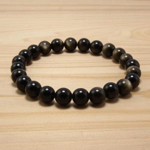 May include: A black beaded bracelet with gold flecks in each bead.