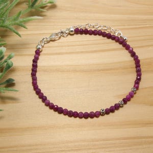 May include: A delicate bracelet made with small, faceted, purple gemstone beads and silver accents.