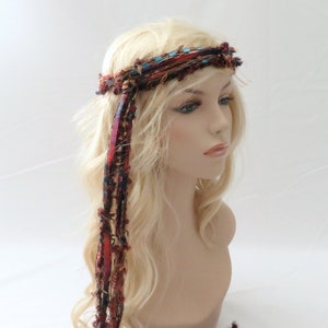 Peut inclure: Un bandeau en tissu tiss&eacute; avec de longues m&egrave;ches color&eacute;es qui pendent. Le bandeau est brun, rouge et bleu avec une touche de turquoise.