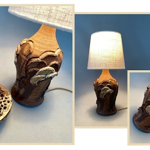 May include: A pair of ceramic table lamps with brown and white glaze. The lamps have a unique design with a textured surface and a stylized floral motif. The lamps are lit and have white fabric lampshades.