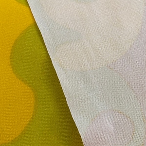 May include: A close-up of two fabrics, one a yellow and green patterned fabric and the other a white sheer fabric.