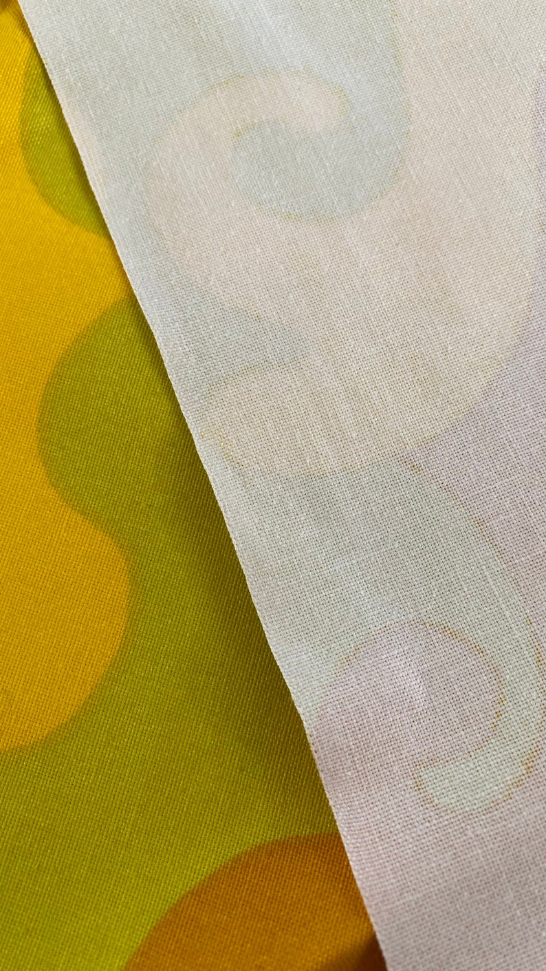 May include: A close-up of two fabrics, one a yellow and green patterned fabric and the other a white sheer fabric.