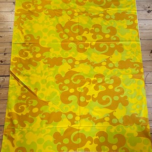 May include: Yellow fabric with a brown and green abstract pattern. The pattern features swirls and circles.