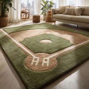 May include: A green and tan baseball field rug with white lines and the letters "AA" in the home plate area. The rug has a soft, plush texture and is designed to resemble a baseball field.