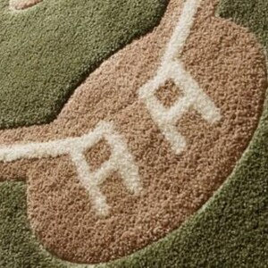 May include: A baseball-themed rug with a green field, tan infield, and white lines. The rug features the letters "RR" in white on the infield. The rug is made of a soft, textured material.