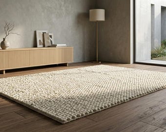 Alfombra de guijarros de lana gruesa, tejida a mano, con textura color crema, estilo minimalista escandinavo.