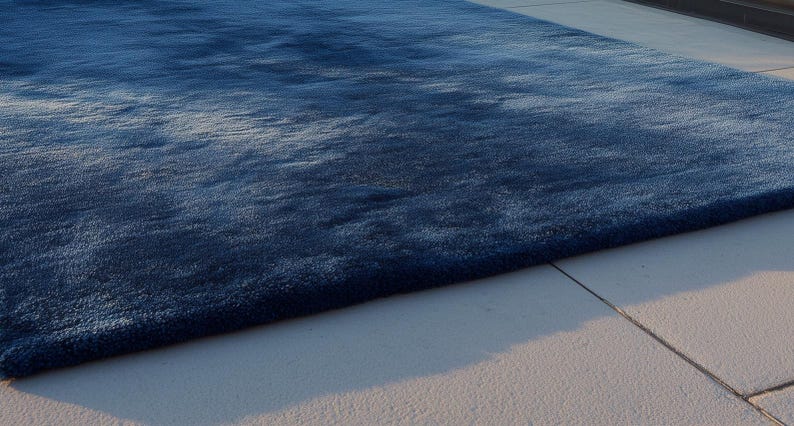 May include: A large, rectangular, plush rug in shades of blue. The rug has a soft, textured appearance and is placed on a light-colored tiled surface. The rug's color gradient creates a sense of depth and visual interest.