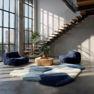 May include: A modern living room featuring two navy blue beanbag chairs, a round wooden coffee table, and a multi-toned blue and white area rug. Large windows and a wooden staircase add to the contemporary design.