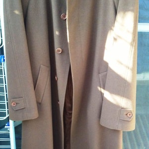 May include: A brown wool coat with a collar and a single row of buttons. The coat has two pockets on the front and is made in Italy.